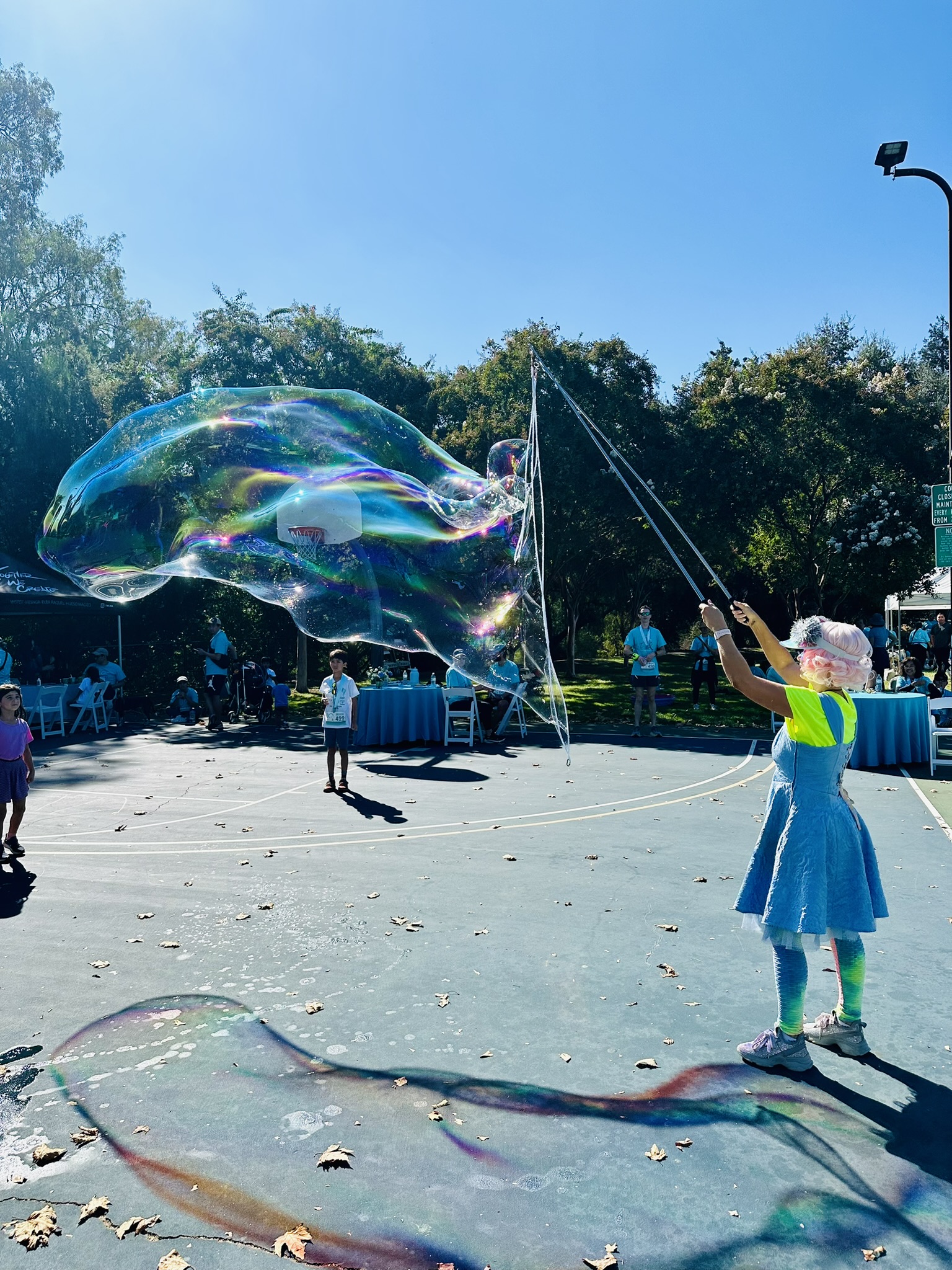 Miss Molly making a giant bubble on an outdoor basketball court