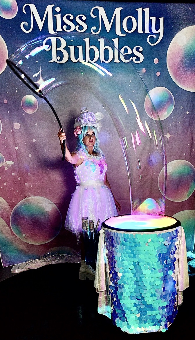 Miss Molly creating a giant bubble above an illuminated bubble table