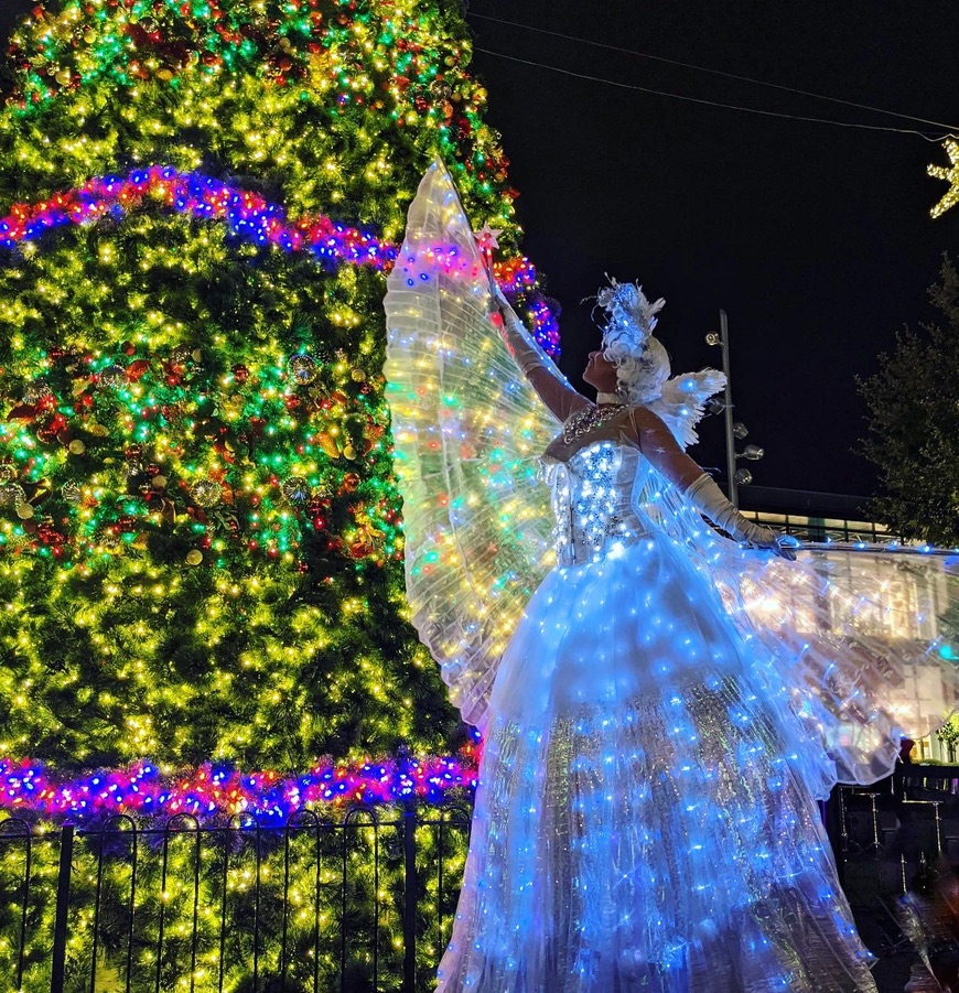 Miss Molly in an illuminated Snow Queen costume beside a Christmas tree